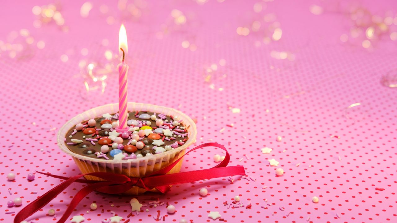 muffin cupcake candle light red ribbon pink background